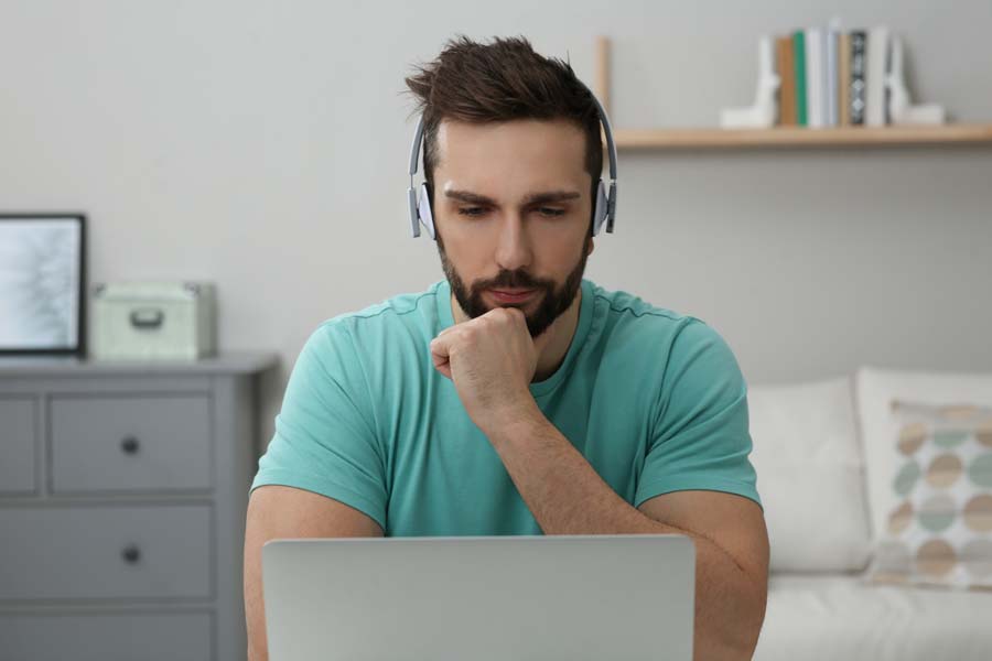 Pensive man reading something on his laptop screen
